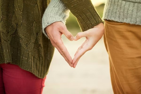 Two hands forming the shape of a heart in warm light