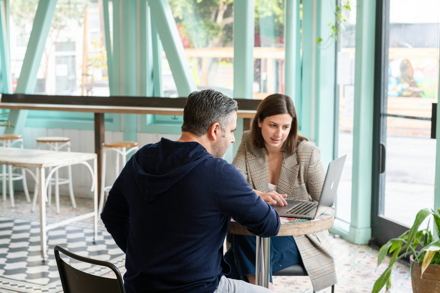 A manager and a team member working through something together over a laptop, at ease