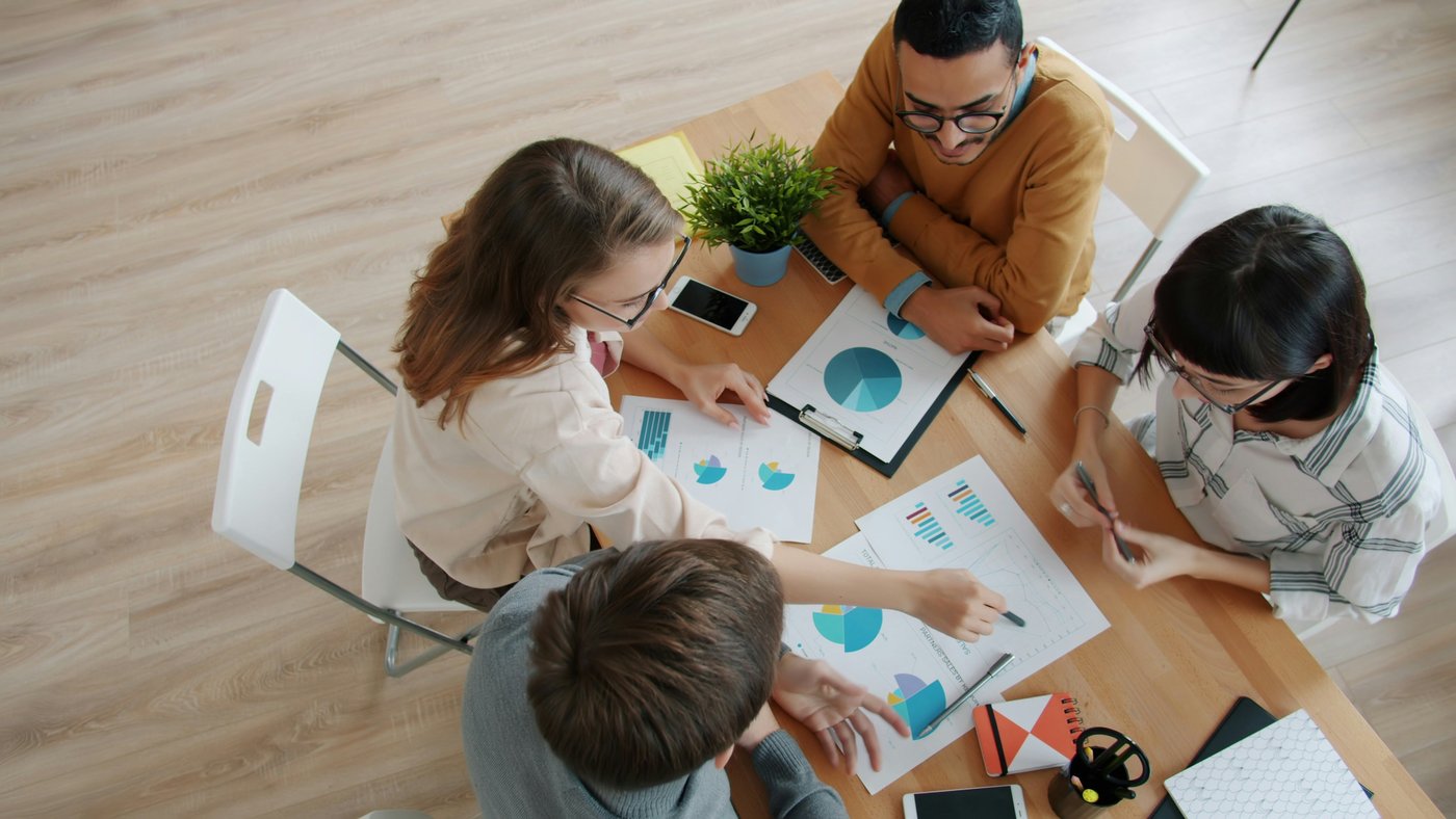 A team gathered over charts and figures at a table, working a problem together