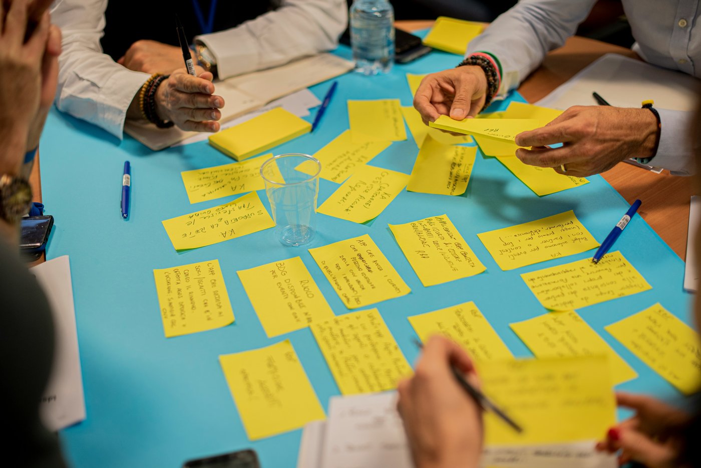 Hands at a table covered in handwritten notes, mid-activity